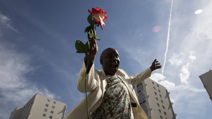 Photo d'un habitant joyeux tenant une rose à la main prise en contre plongée pour la fête du printemps lors du «Samedi à Santy»