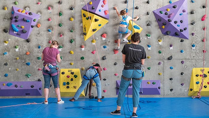 Deux enfants en train de faire de l'escalade sur le mur coloré du gymnase Cavailloud.